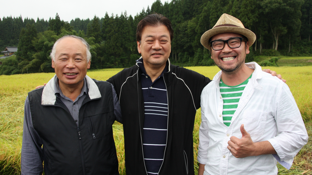稲刈りイベントには日南町の増原聡町長も参加(写真中央)。米作りリーダーの三上惇二氏(左)、アップファームの高橋隆造氏（右）とともに